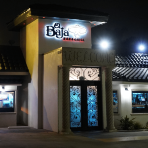 Nighttime view of El Baja Grill, a Mexican food restaurant exterior featuring illuminated signage, patterned roofing, and decorative doorway.