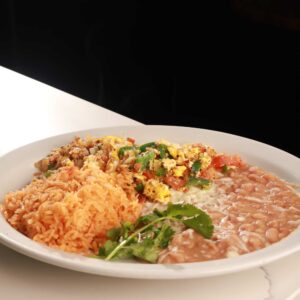 A plate of authentic Mexican food featuring seasoned rice, refried beans, and a scrambled egg mixture with tomatoes and green peppers, garnished with fresh cilantro.