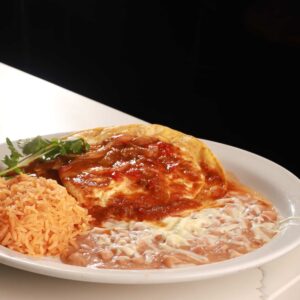 A serving of authentic Mexican enchiladas topped with red sauce beside rice and refried beans, garnished with fresh cilantro on a white plate against a dark background.